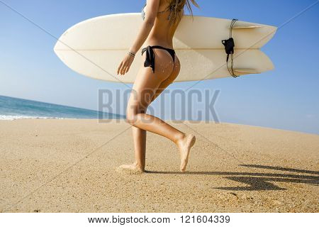 Beauitful young surfer girl running to the waves with her surfboard