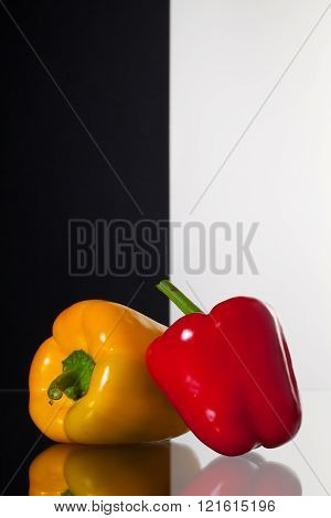 Two peppers isolated on black and white background and glass desk