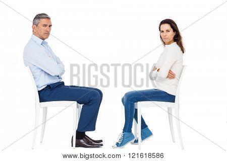 Couple arguing while sitting against white background