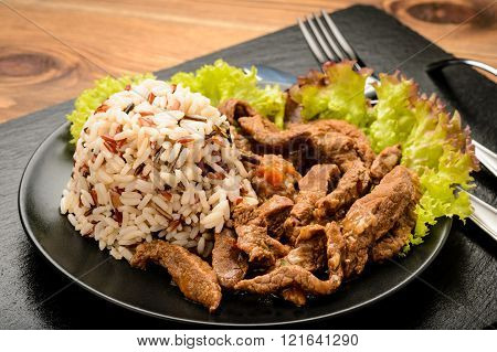 Stewed beef with boiled 3 colour mix rice on blck plate.