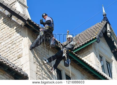 Abseiling building maintenance workers at work.