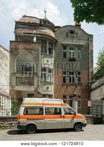 BRASOV ROMANIA - JUL 5 2016: Old Red Cross van in front of an old vintage house - headquarter of the central branch of Old Cross Romania - Old City of Brasov Romania