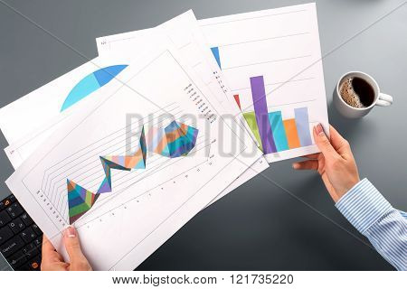 Female hands hold graphic charts.