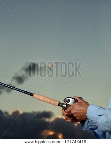 close up image of a man holding a rod and reel while fishing