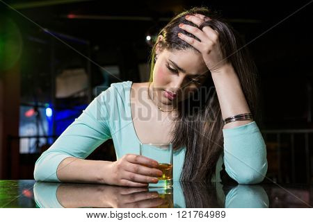 Depressed woman having whiskey at bar counter in bar