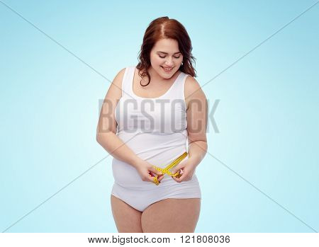 weight loss, diet, slimming, size and people concept - happy young plus size woman in underwear measuring tape over blue background
