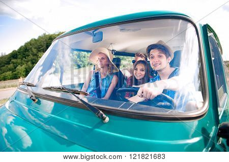 Hipster boy driving an old campervan with teenagers, roadtrip