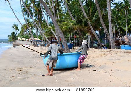 MUINE, VIETNAM - December 20, 2011. Fishermen drag the round boat to the sea near Mui Ne Vietnam