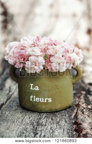 Shabby chic flowers in clay pot on rustic wooden background