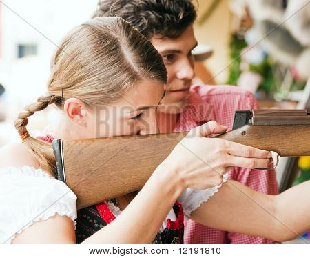 Couple in traditional German or Bavarian costume doing some target shooting at a gallery