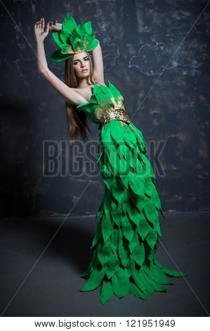 Beautiful sexy young girl woman lady model posing with hand in long paper green dress hair eccessories golden belt in fashion photo studio grey background