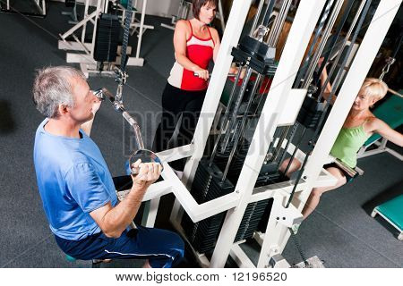 Senior mennesker i et fitnesscenter udøvelsen på en pulldown maskine