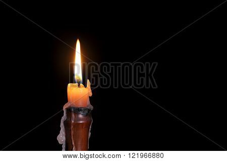 Single wax candle flame burning in darkness.