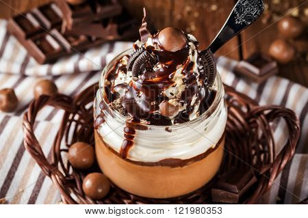 Delicious dessert - chocolate mousse decorated with whipped cream in a glass jar