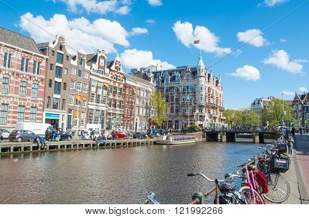 Amsterdam-April 30: Rokin canal with bikes parked along the bank Hotel de l'Europe is visible on the left tourists enjoy cityscape on the opposite side on April 30 2015 the Netherlands.