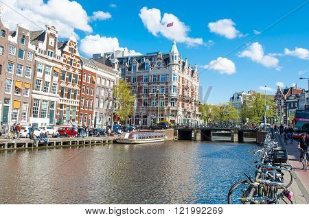 Amsterdam-April 30: Rokin canal with bikes parked along the bank famous Hotel de l'Europe is visible in the background people enjoy cityscape on April 30 2015 the Netherlands.