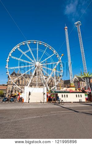 AMSTERDAM NETHERLANDS-APRIL 27, 2015: Attractions on Dam Square on the eve of King's Day on April 27 2015 in Amsterdam. King's Day is the largest open-air festivity in Amsterdam.