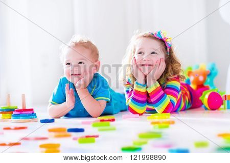 Preschooler child playing with colorful toy blocks. Kids play with educational wooden toys at kindergarten or day care. Preschool children build tower with wood block. Toddler kid in nursery.