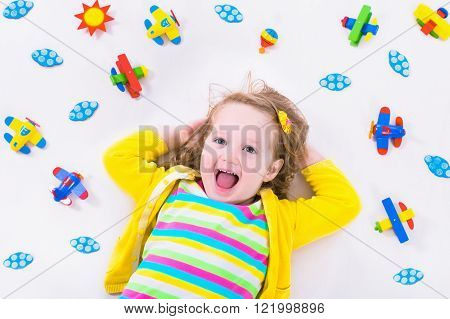 Child playing with wooden airplanes. Preschooler kid flying around the world. Kids travelling and playing. Children at day care or kindergarten. View from above.