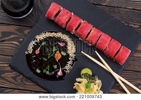 Japanese roll with tuna. Roll with ginger and unagi sauce on a black slate.