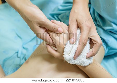 Sick child with high fever laying in bed with mother hand sponging to reduce temperature down.