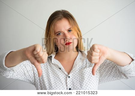 Upset strict woman unsatisfied with result and showing thumbs down. Displeased businesswoman giving bad assessment. Bad quality concept