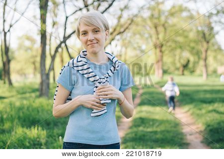 portrait of young cheerful woman with son runnning on background