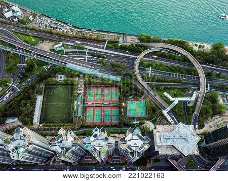 Highway surrounded by high buildings, football, tennis, and basketball courts by the ocean