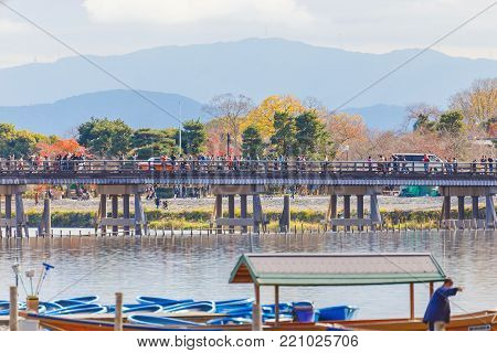 Togetsukyo bridge and boat with the colourful forest mountain background during late autumn season, Arashiyama Japan.