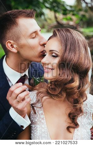 Sensual portrait of a young couple. Wedding photo outdoor.Groom kissing bride