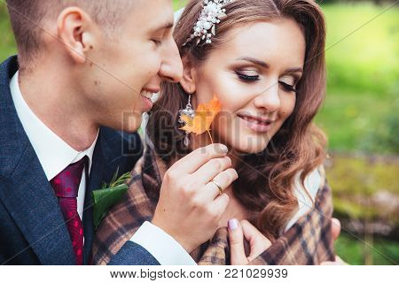 wedding in autumn .Close up portrait of wedding couple sitting in autumn park
