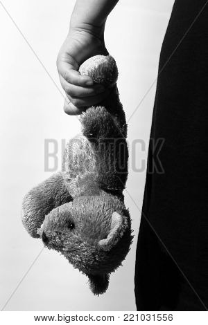 Black and white photo of a girl holding a teddy bear, theme of social problems