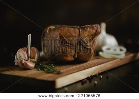 Chunk of salted smoked lard in gauze with a rope.Traditional Russian and Ukrainian meal.Healthy food with pranami spices, herbs, onion and garlic.Food photo for recipe or cookbook. Rustic clolor style
