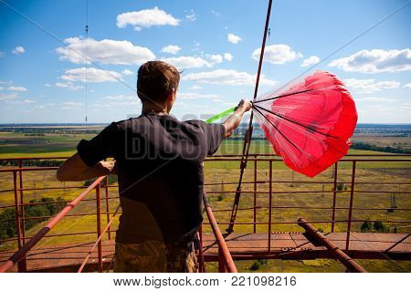 A man is preparing a red parachute for base jumping,