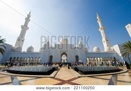 ABU DHABI, UNITED ARAB EMIRATES - DEC 28, 2017: Moslims and tourists are visiting the Sheikh Zayed Mosque in Abu Dhabi. It is the largest mosque in the country.