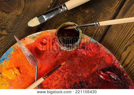 Art palette and brushes for painting on wooden background. The view from the top.