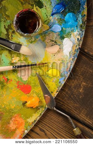 Art palette and brushes for painting on wooden background. The view from the top.