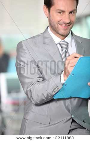 Businessman writing notes in a blue folder