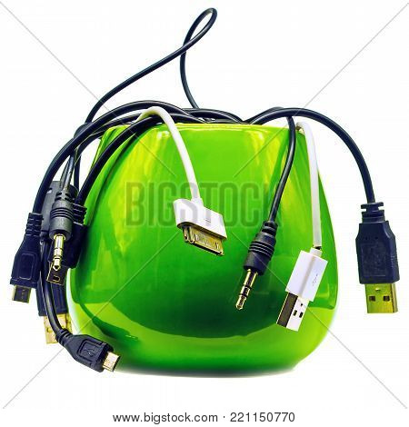 Lot of different cables for cell phones in a green cup. Still life - wire crawl like a snake of green  fruit.