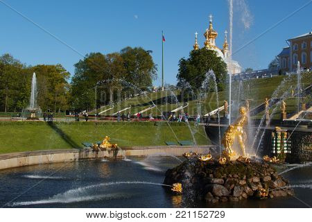 PETERHOF, ST. PETERSBURG, RUSSIA - JUNE 4, 2017: Tourists walking around the Sea canal and the Grand Cascade. The cascade was built in 1715-1724 and is one of the remarkable fountain constructions