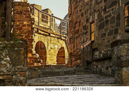 Old lane with houses with stone walls in warm yellow colors of summer sunset.