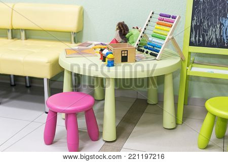childhood, development, pedagogy concept. there is place for playing children equiped with small table and chairs and blackboard, on the table there is colorful abacus and some toys