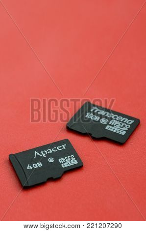 KHARKOV, UKRAINE - DECEMBER 29, 2017: Two small micro SD memory cards Apacer 4gb and Transcend 16gb lies on a red background. Illustrative editorial