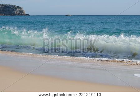 Waves breaking on the shore of a sandy beach