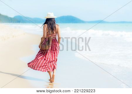 Summer Day.  Smiling woman wearing fashion summer walking on the sandy ocean beach. Happy woman enjoy and relax vacation.  Lifestyle and Travel Concept.