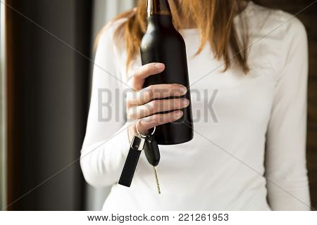 Do not drink and drive concept. Woman holding bottle of beer and car keys in hand
