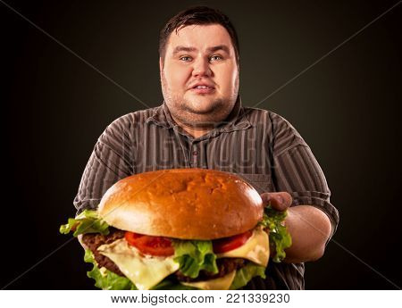 Man eating fast food hamberger. Fat person cooked terrific cheeseburger and admires him, intending to eat it. Junk meal leads to obesity. Consumption of semi-finished products.