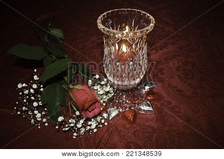 Valentine's day table setting with red rose, candlelight and heart shaped chocolates