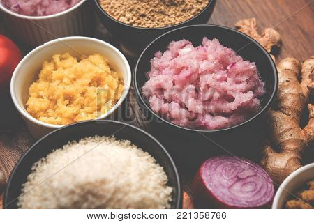 Ginger, Garlic, onion and tomato paste and powder in and raw form. Group of Basic Indian food ingredients over wooden background. Selective focus