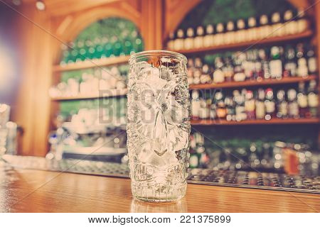 Washed professional bar equipment and a glass filled with ice arranged on the bar counter